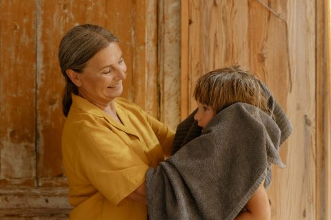 Mujer sonriente secando a un niño con una toalla.